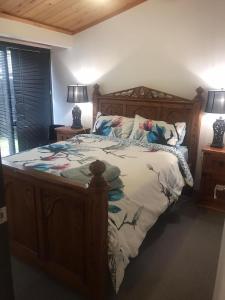 a bedroom with a large bed with a wooden frame at Sandy Toes Holiday Home Orewa in Orewa