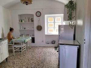 Romantic Casa Rurale Le Masche في Rivara: امرأة تجلس على طاولة في مطبخ