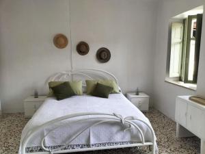 Romantic Casa Rurale Le Masche في Rivara: غرفة نوم بيضاء مع سرير أبيض مع وسائد خضراء