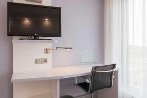 una scrivania con TV e una sedia in camera di prizeotel Affoltern Am Albis ad Affoltern