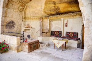 a stone room with a table and a bench in a building at Gibos Cave Hotel in Urgup