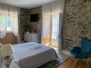 um quarto com uma cama e uma cadeira azul em Quintal do Grémio em Torre de Moncorvo