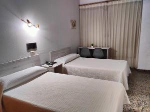 Habitación de hotel con 3 camas con sábanas blancas en Hotel Cogullada, en Zaragoza
