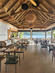 un comedor con mesas, sillas y ventanas en Cook's Bay Hotel & Suites en Paopao