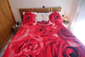 a red comforter with red roses on a bed at beautiful apartment by the beach in Saïdia