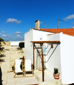 a white building with two chairs and a table at Casa da Serra in Nazaré