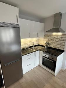 cocina con armarios blancos y nevera de acero inoxidable en Apartamento Cué, en Gijón