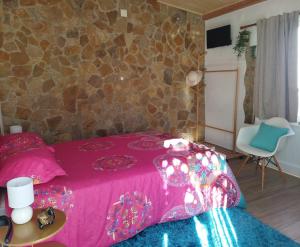a bedroom with a pink bed and a stone wall at Casa da Serra in Nazaré