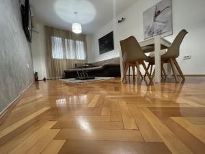 un soggiorno con pavimento in legno, tavolo e sedie. di Apartments Ciki a Podgorica
