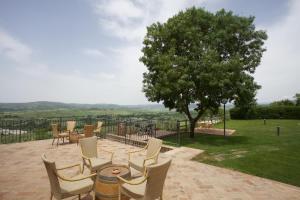 eine Terrasse mit Stühlen, einem Tisch und einem Baum in der Unterkunft Bio Agriturismo Il Torrione in Saturnia