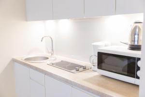 cocina blanca con fregadero y microondas en VacationClub - Ischgl Apartament 19, en Sienna