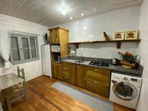 a kitchen with wooden cabinets and a washer and dryer at Chalé Terra Luni in Urubici