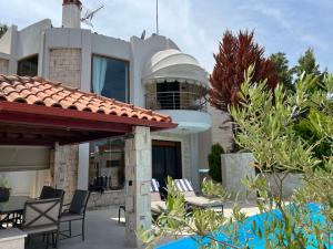 a house with a patio with chairs in front of it at Sunny Seaside Villa-90 m from beach in Kriopigi
