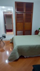 a bedroom with a green bed with a wooden floor at FLAT CAVALINHO BRANCO in Águas de Lindóia
