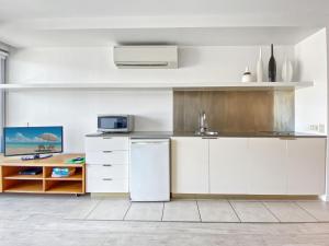 uma cozinha com armários brancos e um frigorífico branco em Blue on Blue Superior Studio Room 1321 em Nelly Bay