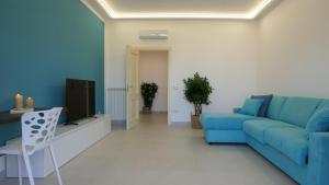 un soggiorno con divano blu e TV di Maison Lucia a Castellammare di Stabia