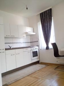 una cocina con armarios blancos, una silla y una ventana en Apartmani Aeredrom, en Sarajevo