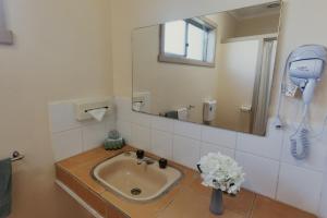 a bathroom with a sink with a mirror and a phone at Woodmans Hill Motel in Ballarat