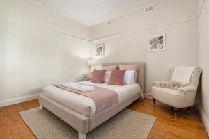 um quarto branco com uma cama e uma cadeira em Sampson Cottage - Historic Charm em Orange