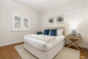 a white bedroom with a large white bed with blue pillows at Sampson Cottage - Historic Charm in Orange +15 photos