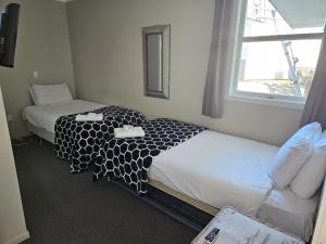 Cette chambre comprend 2 lits et une fenêtre. dans l'établissement FatOwl Motel, Bar & Eatery, à Piopio