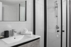 a white bathroom with a sink and a shower at דירה בקומפלקס עם בריכה 100 מטר מהים - By Edomlux in Eilat +10 photos