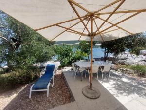 a table and chairs under a large umbrella at Apartments by the sea Zuronja, Peljesac - 13202 in Putniković