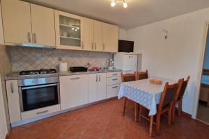 a kitchen with white cabinets and a table with chairs at Apartments by the sea Zuronja, Peljesac - 13202 in Putniković