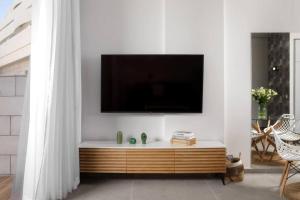 a living room with a tv on a white wall at דירת גן במתחם סי סייד 100 מטר מהים - By Edomlux in Eilat