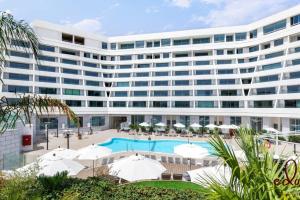 - un grand bâtiment blanc avec une piscine et des parasols dans l'établissement דירת גן במתחם סי סייד 100 מטר מהים - By Edom, à Eilat