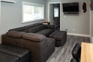 a living room with a brown couch and a tv at Chims Cabins - Port Alberni in Port Alberni