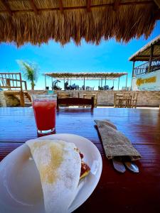 una rebanada de pizza en un plato en una mesa con una bebida en Kite inn house Pousada e Kite Club, en Icapuí