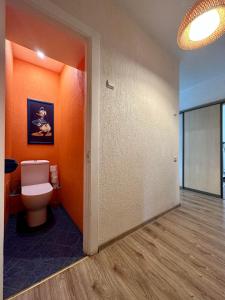 een badkamer met een toilet en een oranje muur bij Riga Mezaparks Apartment in Rīga