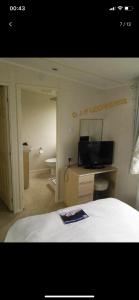 a bedroom with a bed with a television and a desk at Lodge for Hire in Pagham