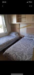 two beds in a small room with a window at Lodge for Hire in Pagham