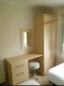 a desk with a mirror and a stool in a bedroom at Lodge for Hire in Pagham