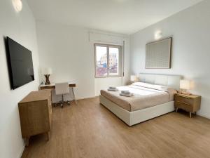 奧爾比亞的住宿－Attico Vespucci Luxury Penthouse，一间卧室配有一张床、一张书桌和一台电视