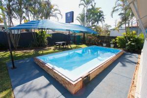 a large swimming pool with an umbrella and a table at Blue Shades Motel in Maryborough