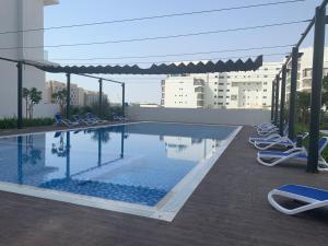 a swimming pool with chairs and umbrellas on a building at Delightful Staycation in Masdar in Al Qurayyah