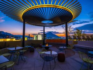 un toit-terrasse avec des tables et des chaises au crépuscule dans l'établissement Galeria Plaza Monterrey, à Monterrey