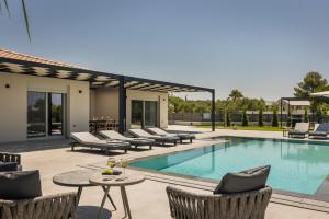 a swimming pool with lounge chairs and a patio at AL MARE VILLAS in Lixouri
