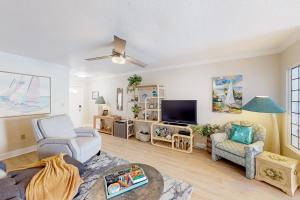 a living room with a couch chairs and a tv at The Shuttle Beach House in Cape Canaveral