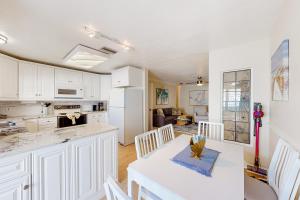 une cuisine avec des placards blancs et une table et des chaises blanches dans l'établissement The Shuttle Beach House, à Cap Carnaveral