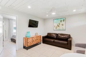 a living room with a leather couch and a tv at Beachside Retreat W Heated Pool in St Pete Beach