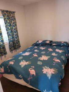 a bed with a blue blanket with pink flamingos on it at Pigeon Lake Cottage in Kawartha Lakes