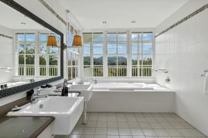 Baño blanco con 2 lavabos y bañera en Nimbo Fork Lodge en Gocup