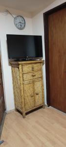 TV en un soporte de madera con reloj en la pared en Patagonia Salvaje Hostel en El Calafate