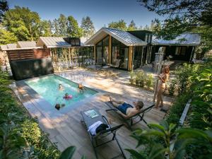 Luxury lodge with private swimming pool, located on a holiday park in Rhenen في رينن: مجموعة من الناس في مسبح في منزل