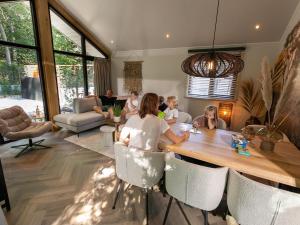 een groep mensen die rond een tafel in een woonkamer zitten bij Luxury lodge with private swimming pool, located on a holiday park in Rhenen in Rhenen