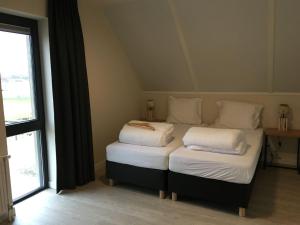 2 camas individuales en una habitación con ventana en Modern design lodge directly at the water, in national park, en Tholen